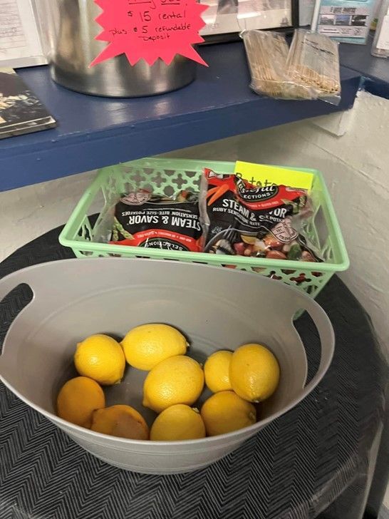 A bowl of lemons sits next to a basket of peppers