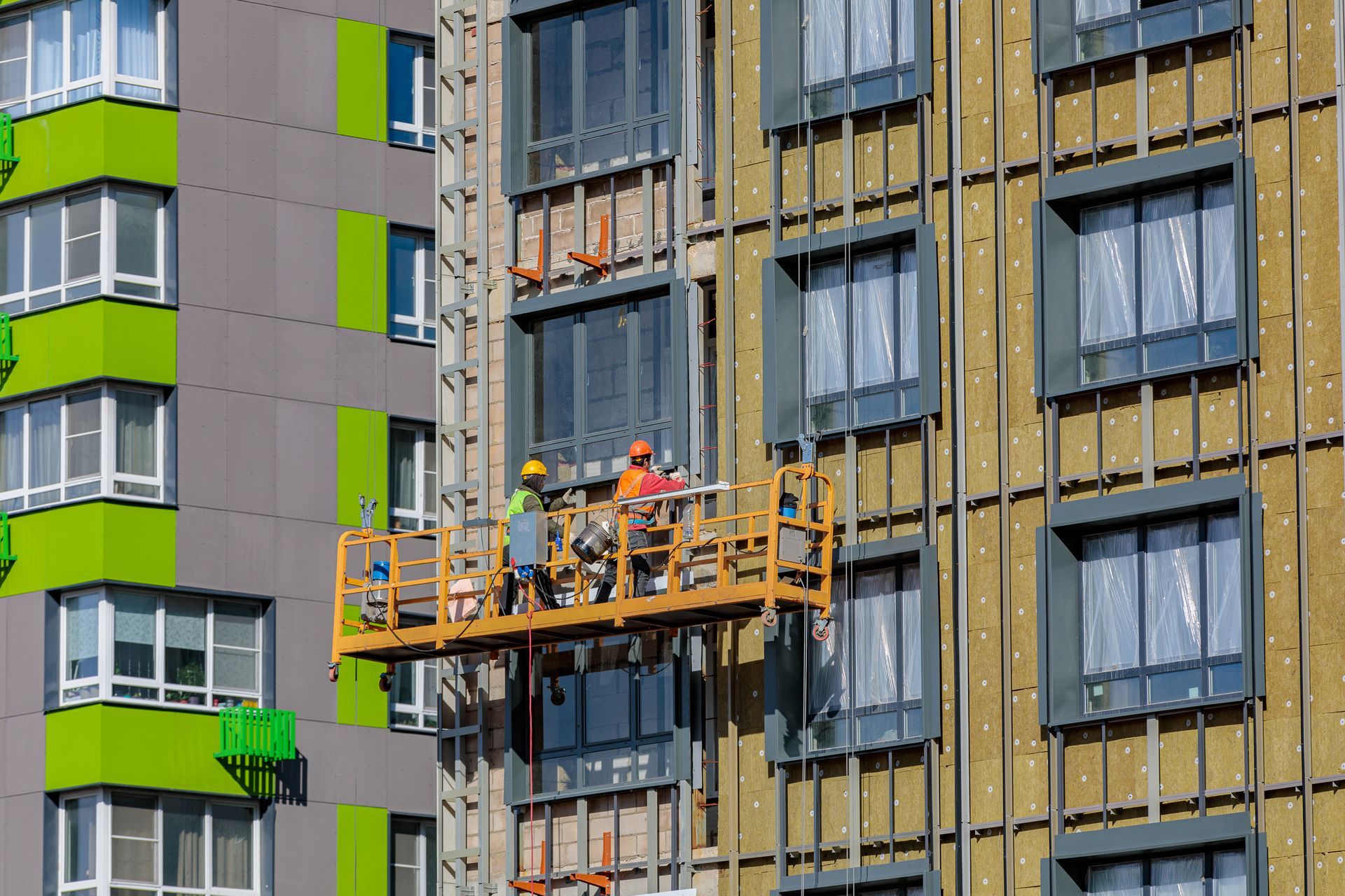 Male builders work on the facade of the building. Male builders work on the facade of the building.