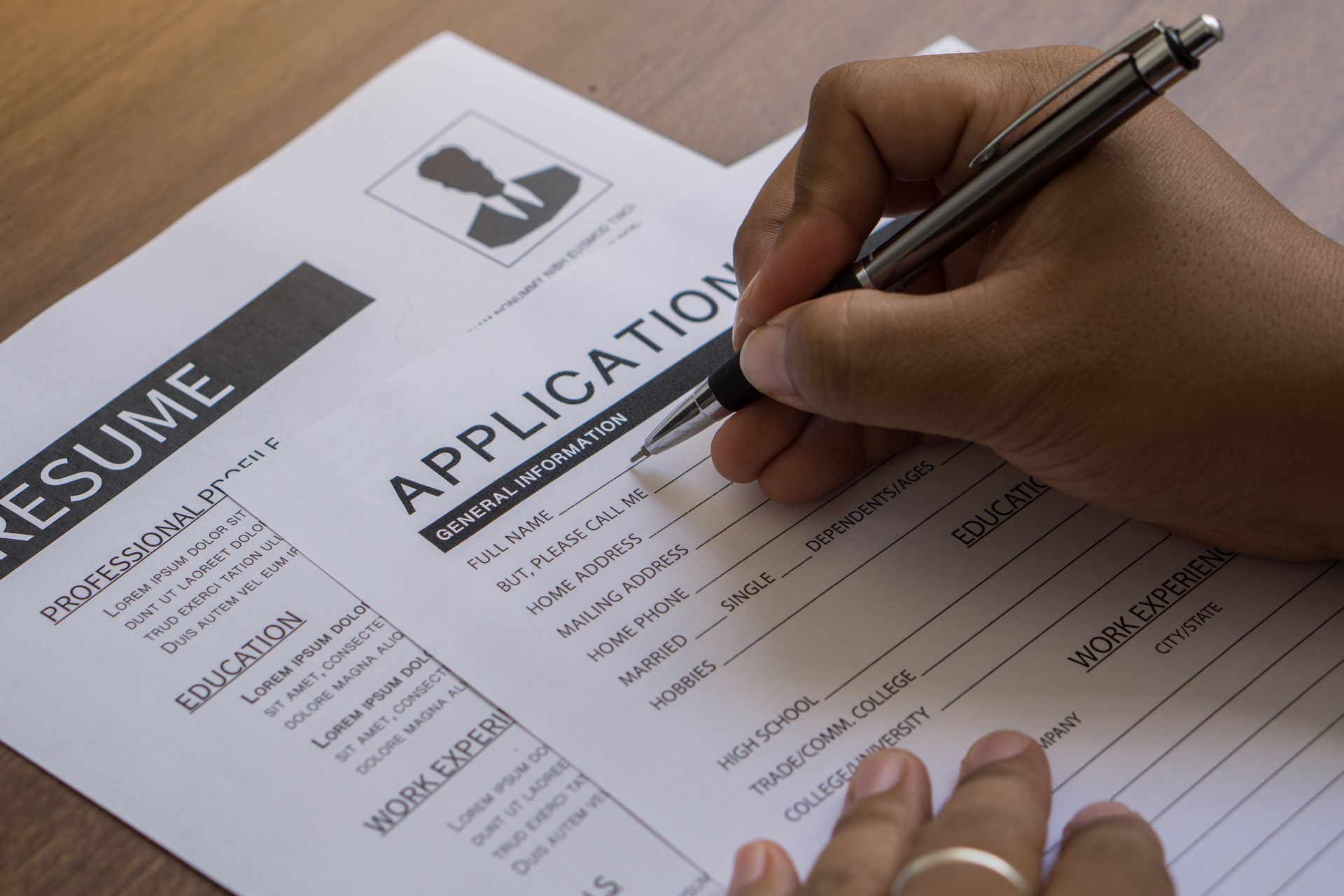 Person with a finished resume filling out a job application