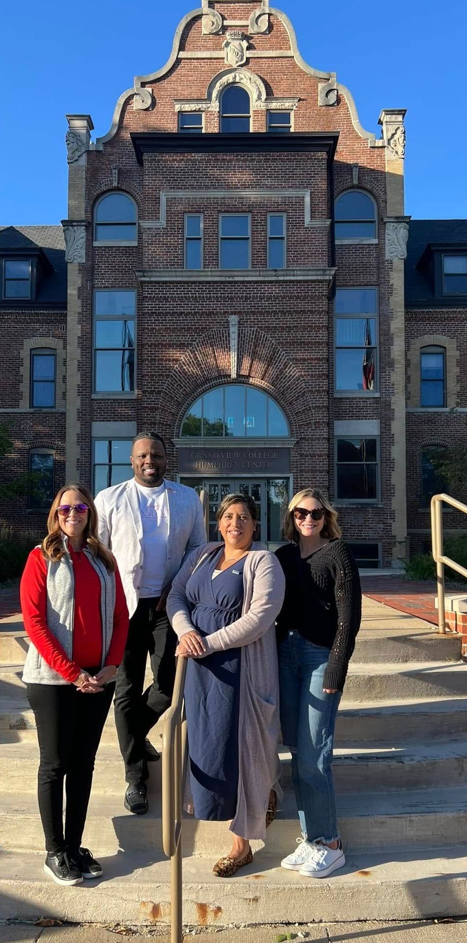 A group of people are standing in front of a large brick building.