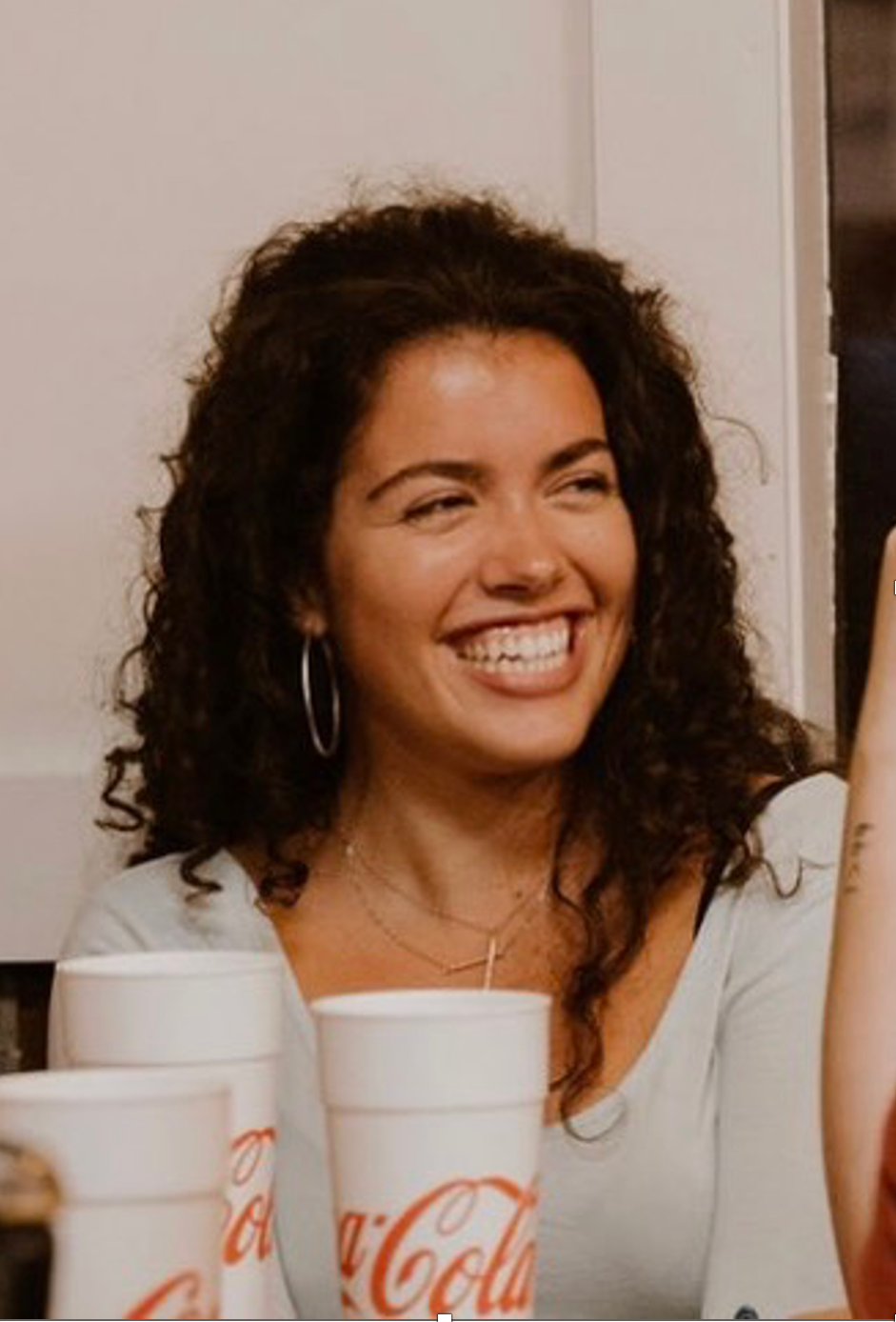 A woman is smiling in front of a coca cola cup