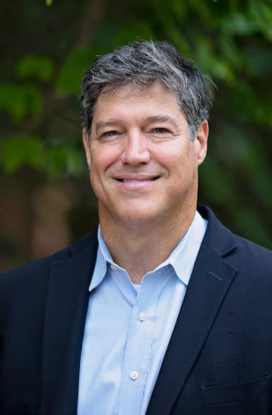 A man in a suit and blue shirt is smiling for the camera.