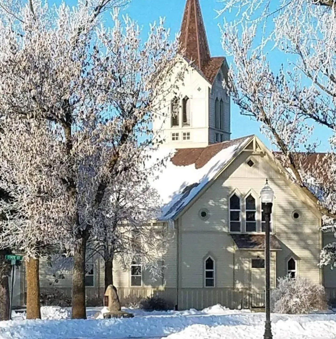 A church with a steeple is surrounded by snow covered trees