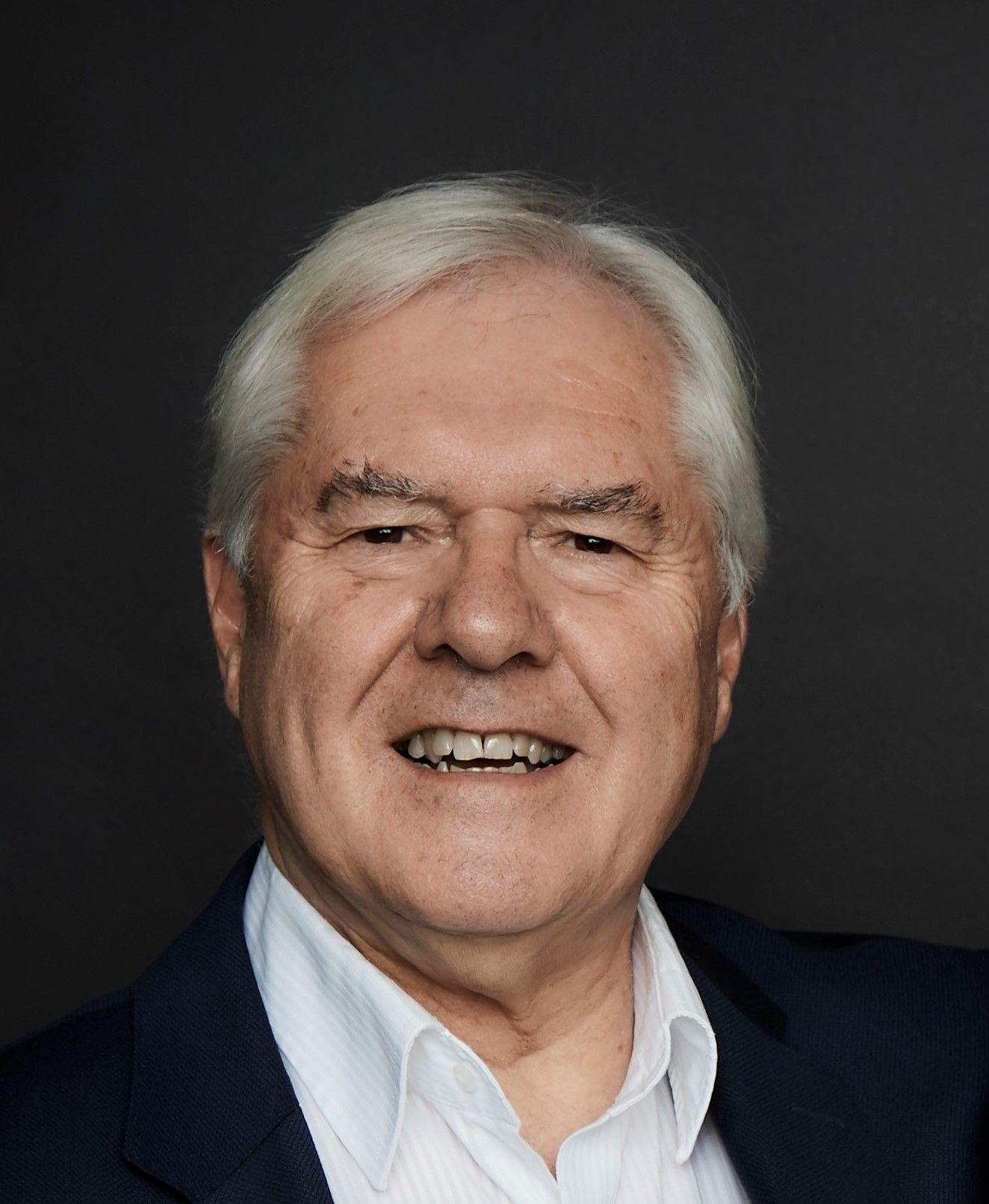 A man in a suit and white shirt is smiling for the camera.