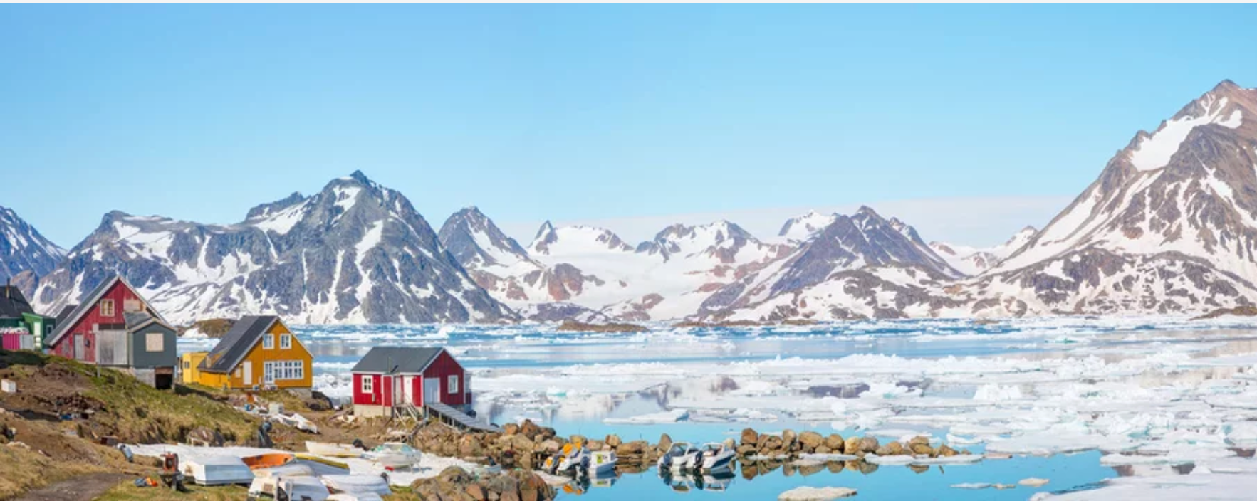 A row of houses sitting next to a body of water with mountains in the background.