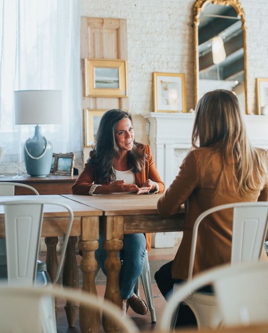 One woman speaking to another woman at a table