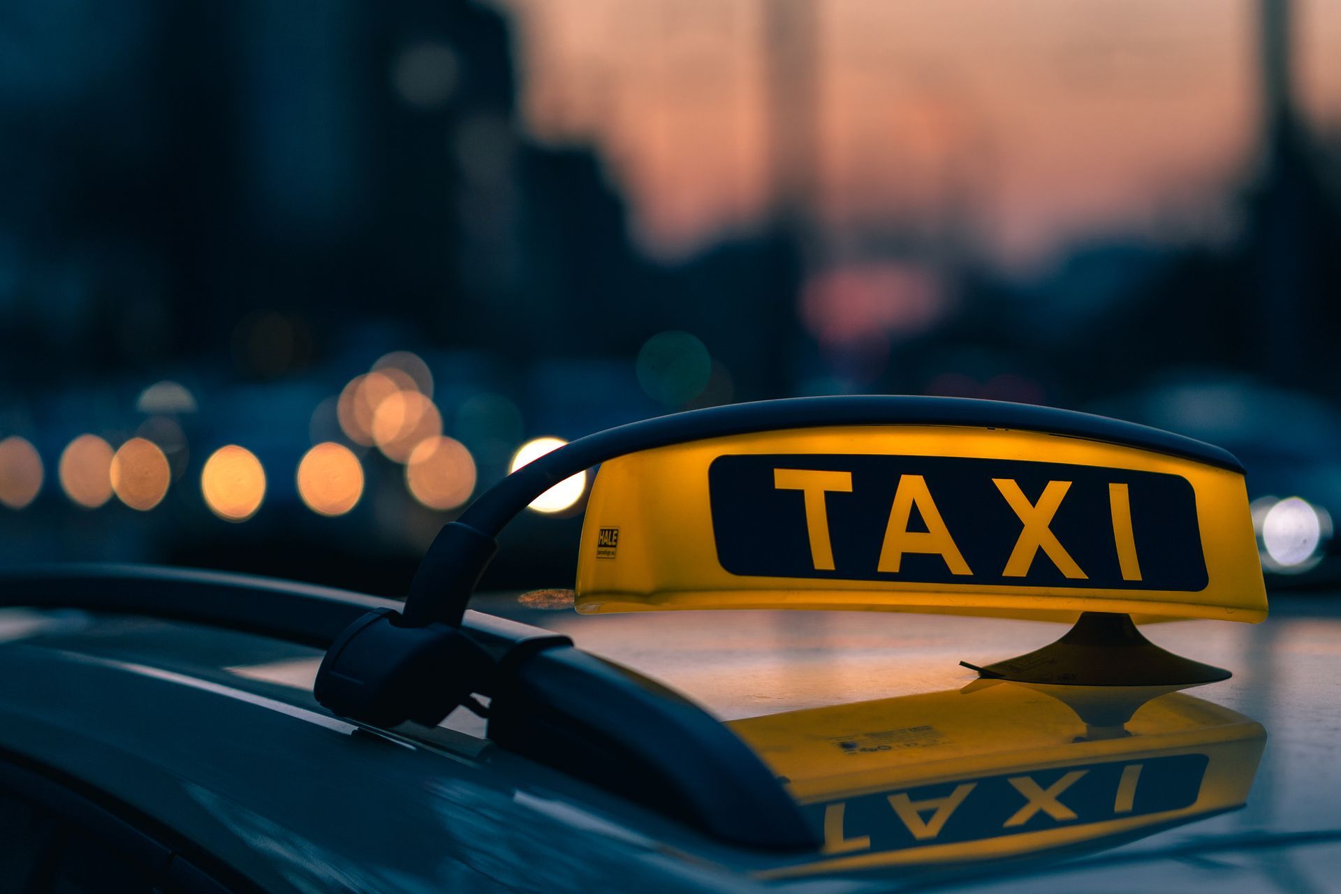 Bilingual taxi driver in Los Angeles standing beside a clean modern sedan.