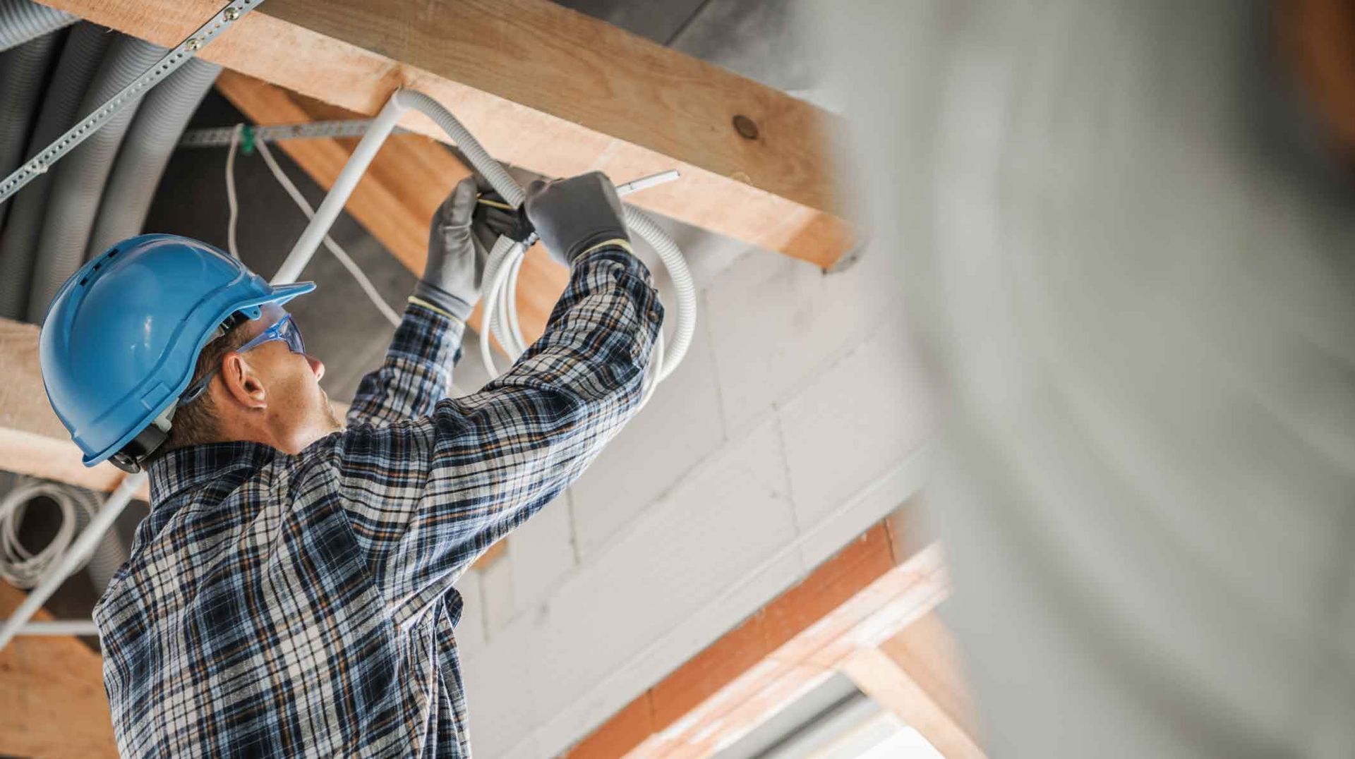 Construction worker in blue hard hat installing ceiling framing indoors Construction worker in blue hard hat installing ceiling framing indoors