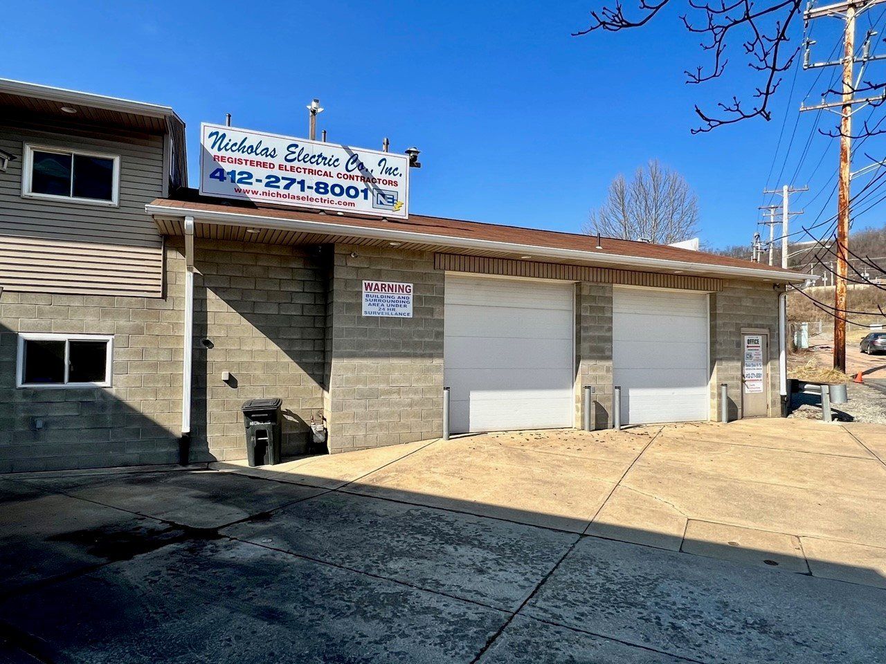 Auto repair shop with a sign, garage doors, and a parked building exterior under a clear blue sky