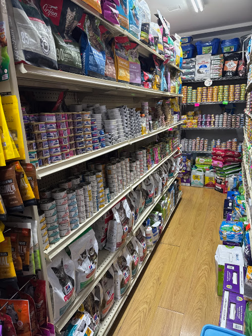 Aisle of a pet store with shelves stocked with pet food, treats, and supplies.