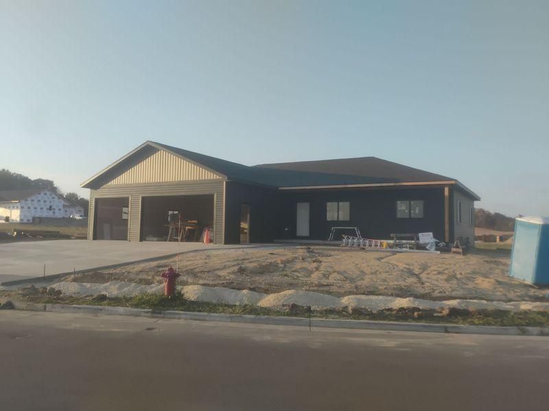 A newly built, dark-sided single-story house with an attached garage under construction.