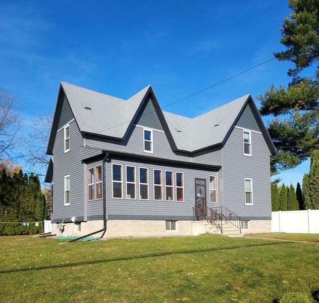 A two-story, grey-sided house with a dark grey roof and multiple gables.
