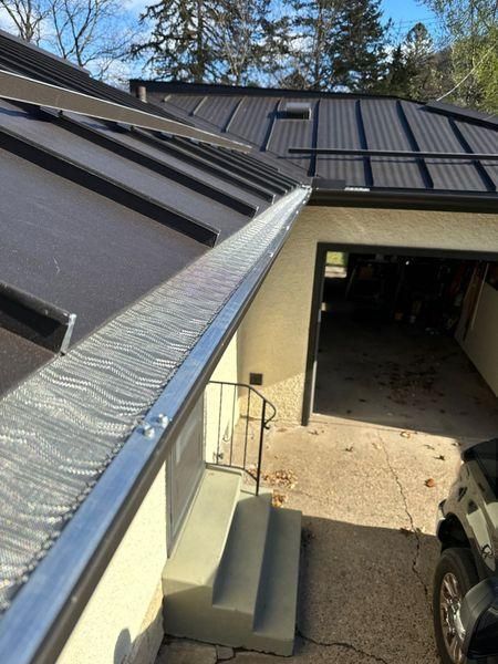 A high-angle view looking down from a metal roof with gutter guards.