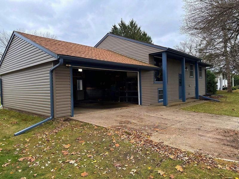 A tan-sided garage with a brown shingled roof and blue trim.
