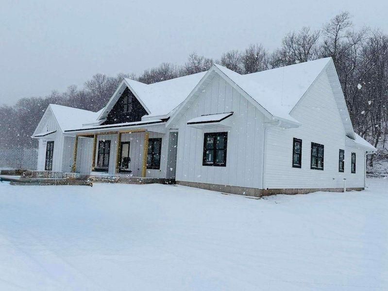 A modern, white farmhouse with black window frames and wood accents.