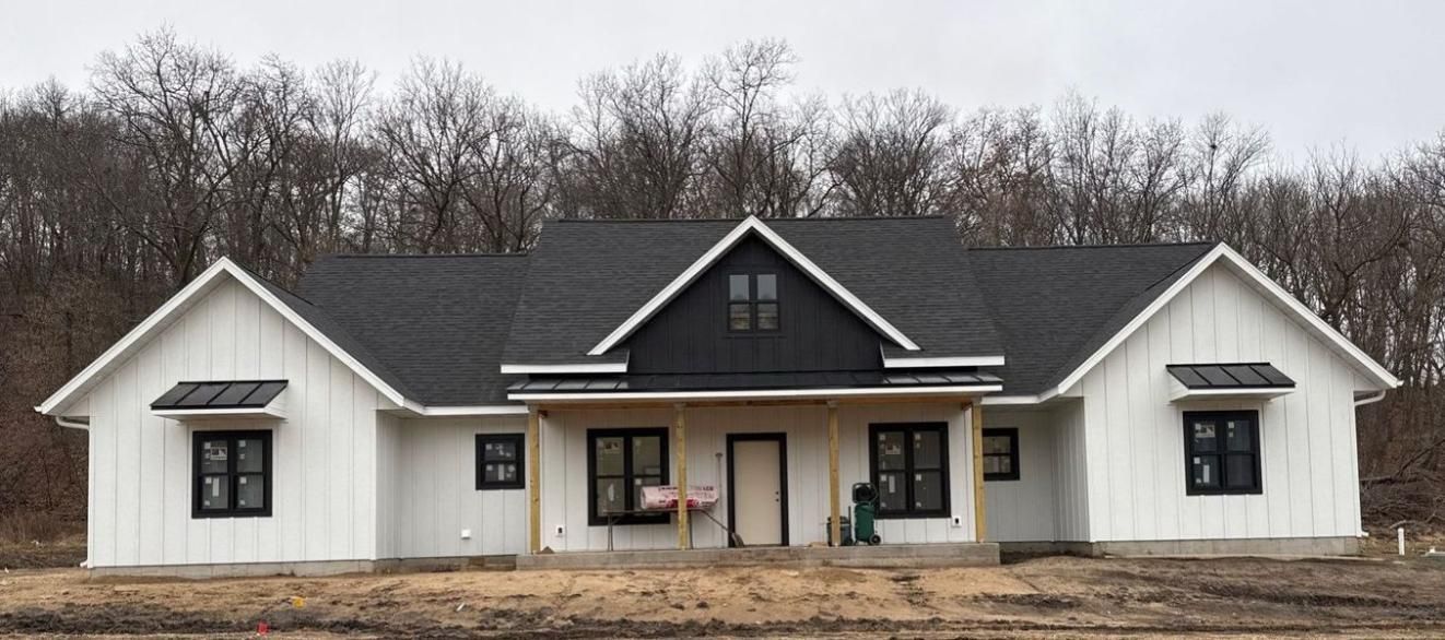 A modern farmhouse with white vertical siding, black-framed windows, a black roof, and a front porch.