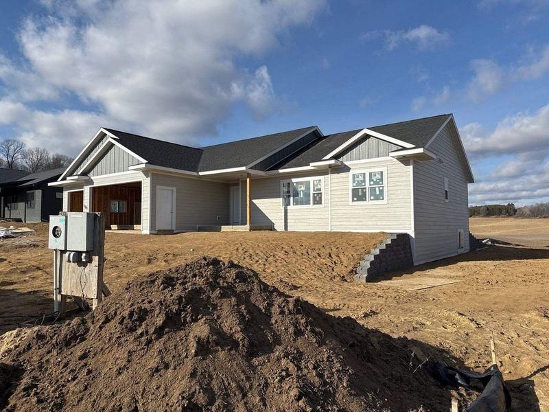 A newly constructed, single-story beige house with a dark gray shingled roof.