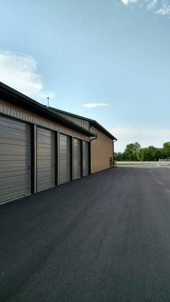 A row of metal storage unit doors along a paved drive.