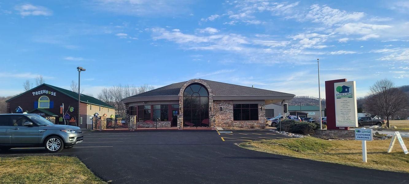 A low-slung, tan brick building with a dark arched entrance next to a dark storefront.