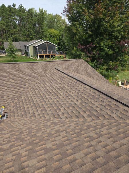 An elevated view of a brown shingled roof with a diagonal ridge.