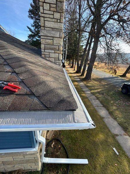 A roof edge with a gutter guard and downspout.