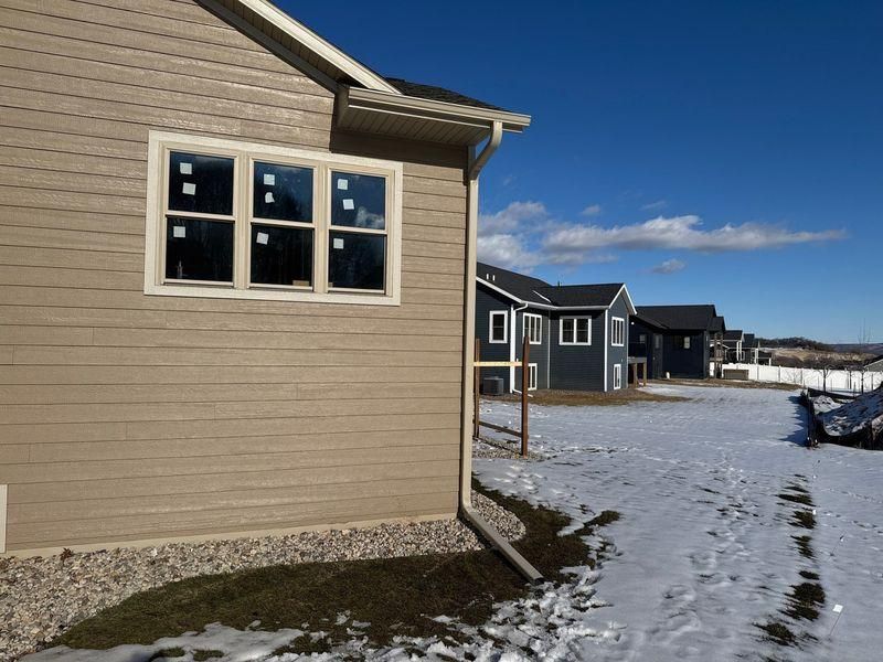A light brown house with a window facing a row of dark blue houses in a snow-covered field.