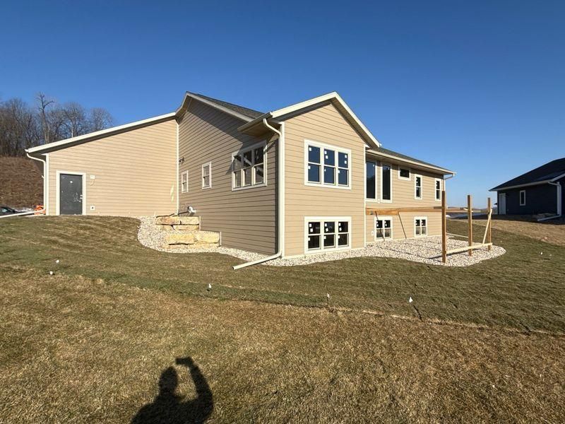 A beige two-story house with a partially completed wooden deck, gravel landscaping, and a side entry door.