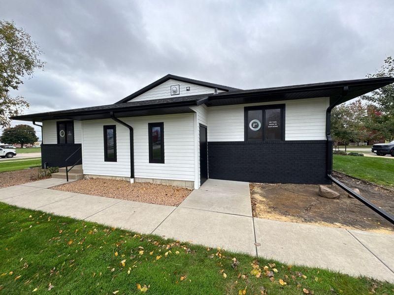 A single-story building with white horizontal siding and a black-painted lower half.