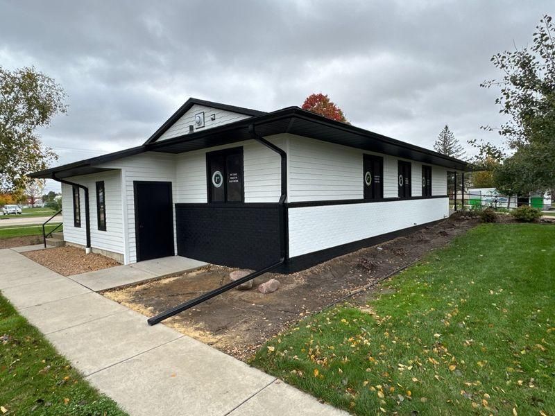 A single-story building with white horizontal siding and a black lower exterior.