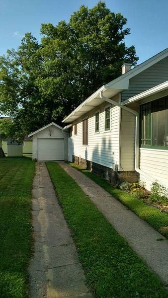 A side view of a white house with a grass-lined concrete driveway.