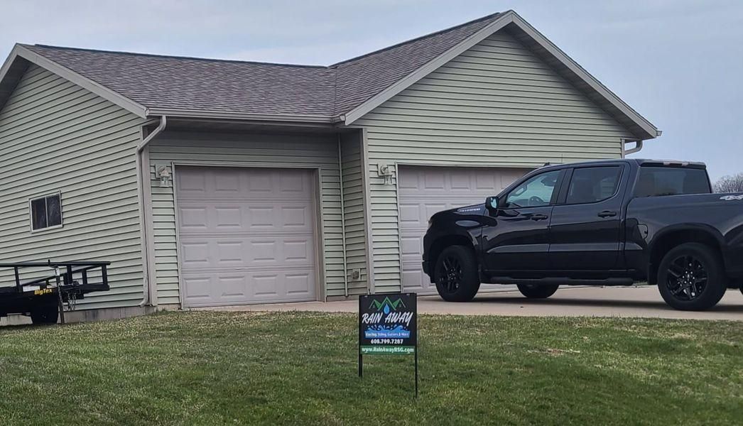 A two-car garage with light siding and a black pickup truck parked in front.