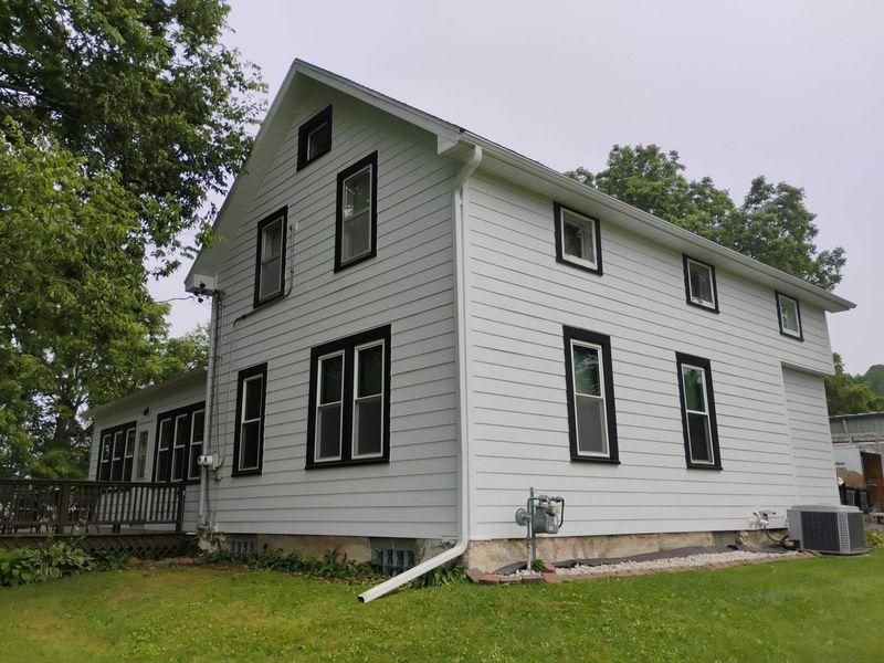 A two-story white house with black window frames, siding, and a gabled roof.