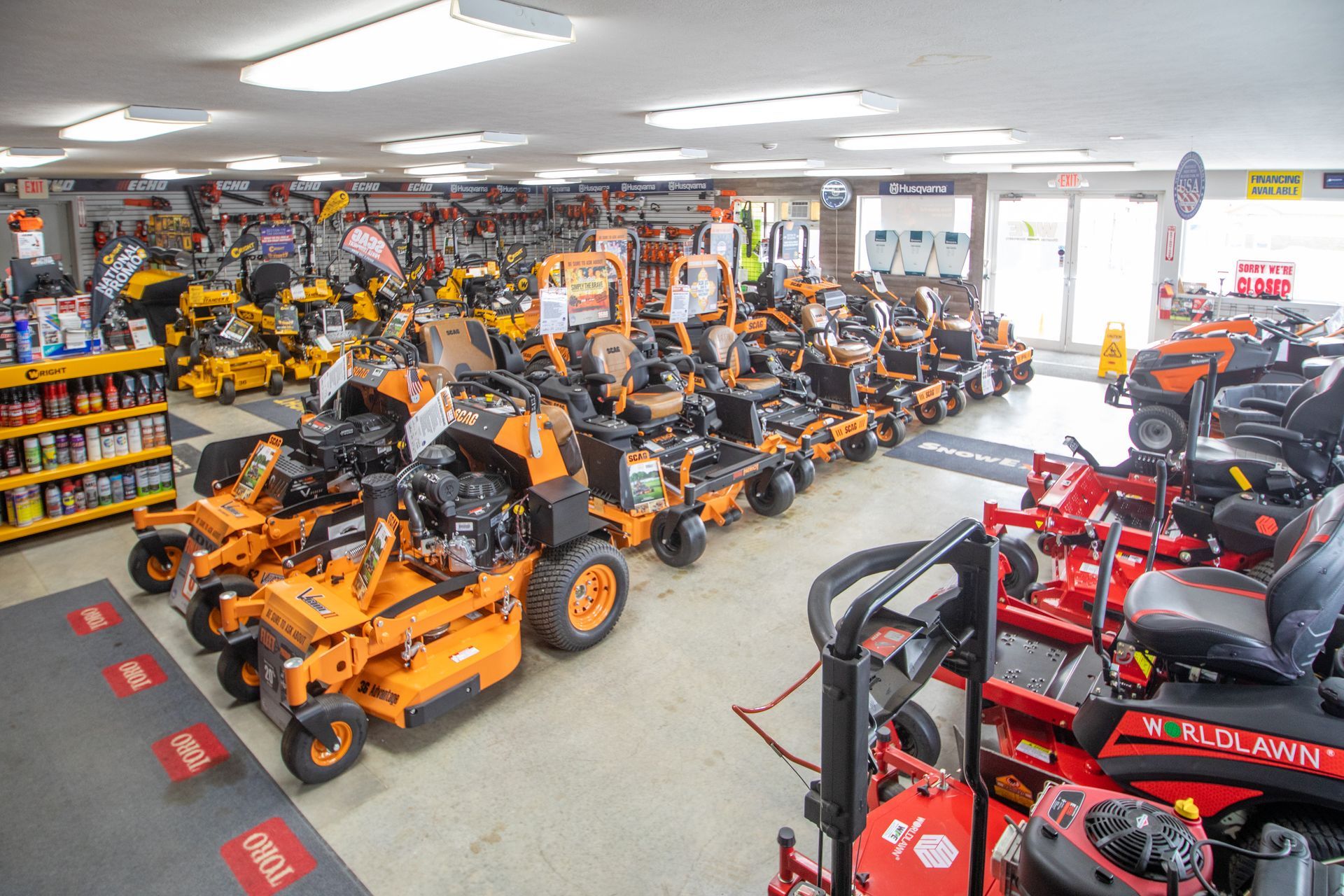 Indoor showroom packed with orange and red zero-turn lawn mowers and outdoor power equipment