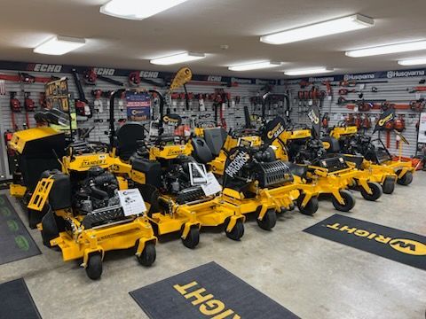Rows of yellow and black riding lawn mowers displayed in a showroom floor.