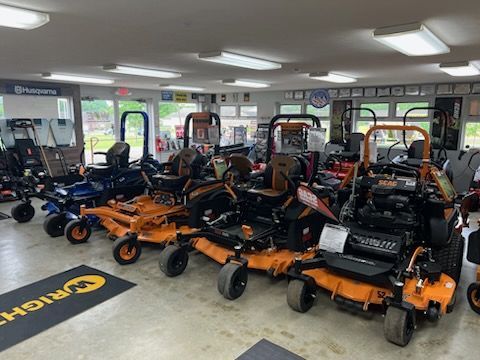 Indoor showroom with rows of orange and black lawn mowers and other outdoor power equipment