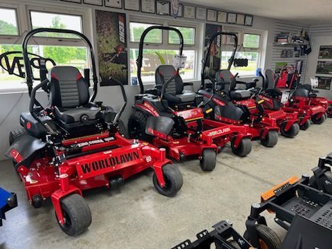 Red Ferris mowers lined up in a showroom or garage, with black seats and large wheels.