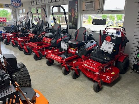 Row of red riding lawn mowers displayed inside a showroom