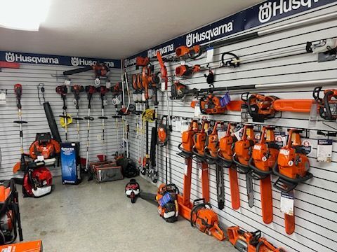 Husqvarna store display with orange chainsaws and trimmers mounted on wall racks.