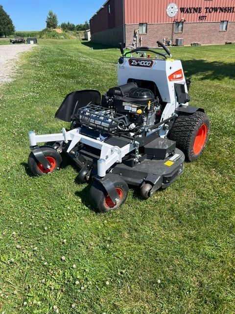Red riding lawn mower parked outside a beige shop with WFE signs on the building.