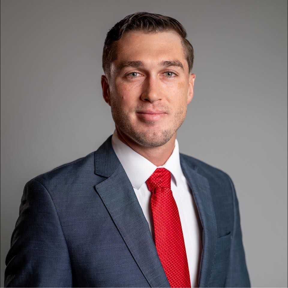 A man in a suit and red tie is smiling for the camera.