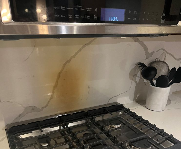 Heat discoloration on a white quartz countertop beneath a microwave