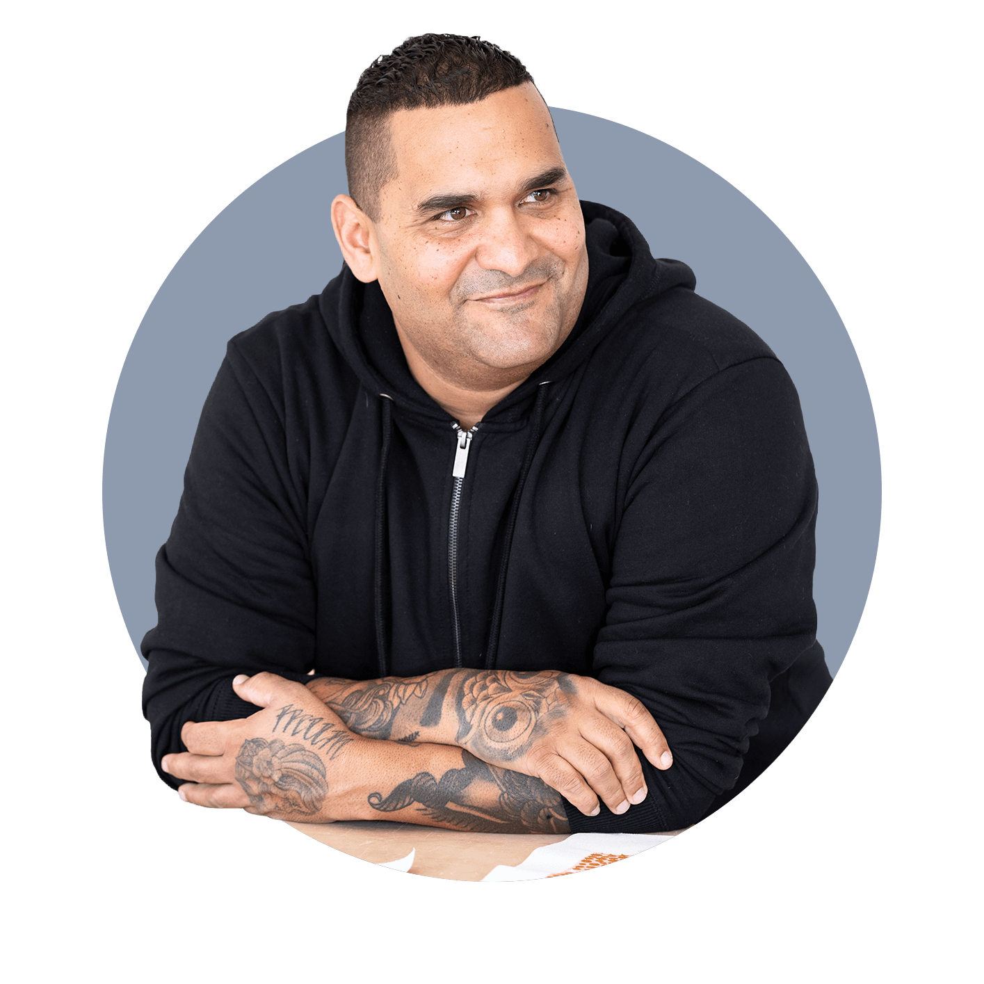 First Nations man with tattoos smiling and looking away from camera