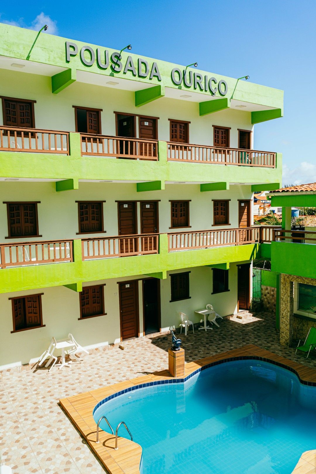 Pousada verde e branca com piscina.