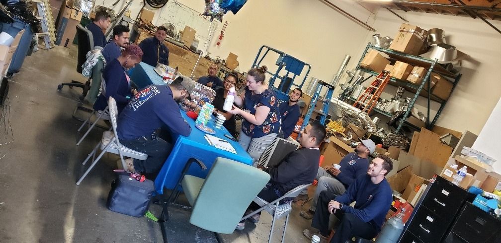A group of people are sitting around a table in a garage.