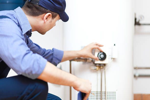 A plumber is working on a water heater in a bathroom.