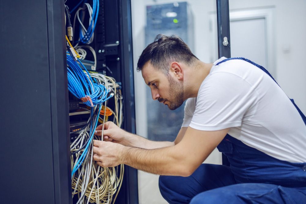 A Man is Working on a Server in a Data Center — AES Electrical Contracting In Winnellie, NT