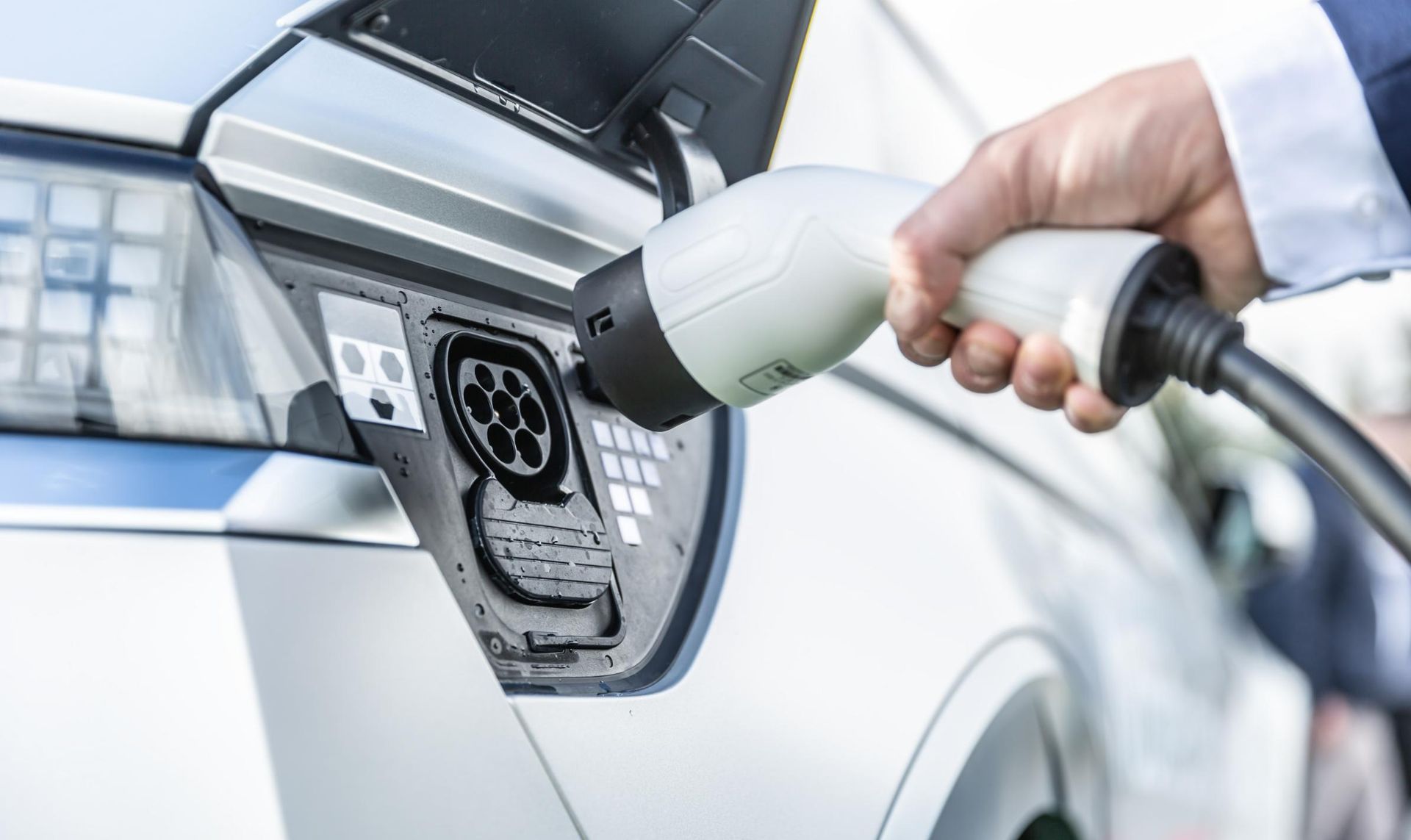 Hand Plugging an Electric Vehicle Charging Cable Into a Car — AES Electrical Contracting In Winnellie, NT