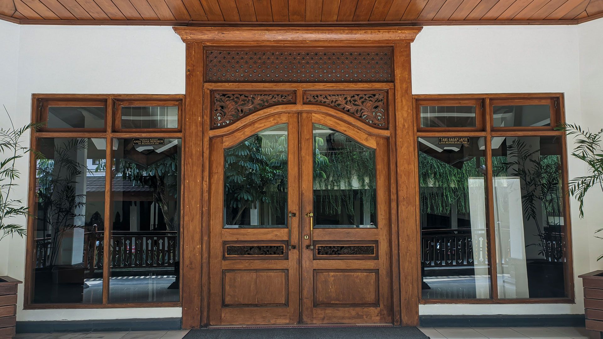 Ornate wooden double doors with glass side panels on a building entrance