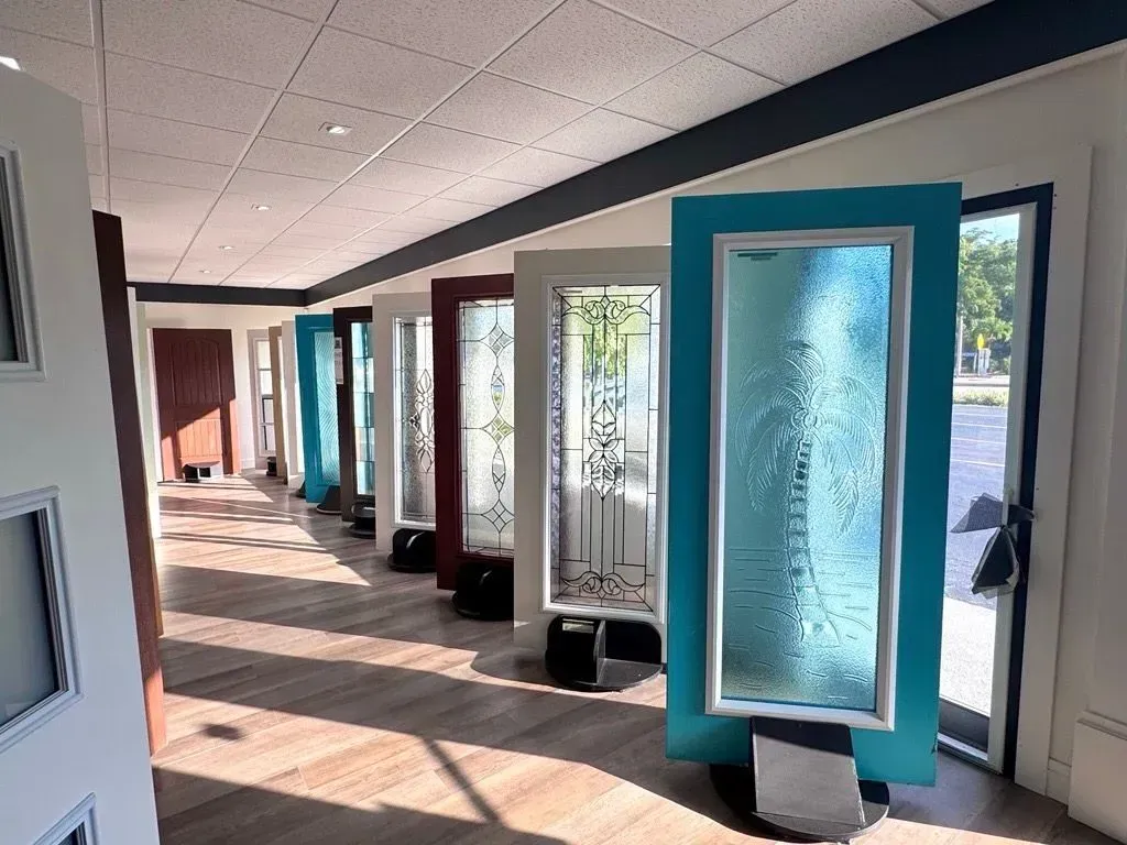 Modern hallway with teal-framed glass panels and sunlight streaming across the floor.