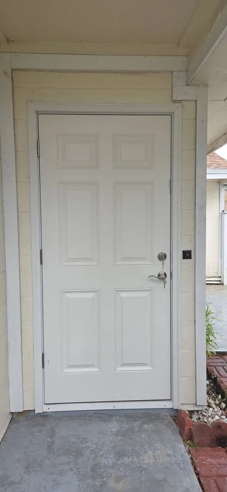White front door with decorative panels under a covered entryway